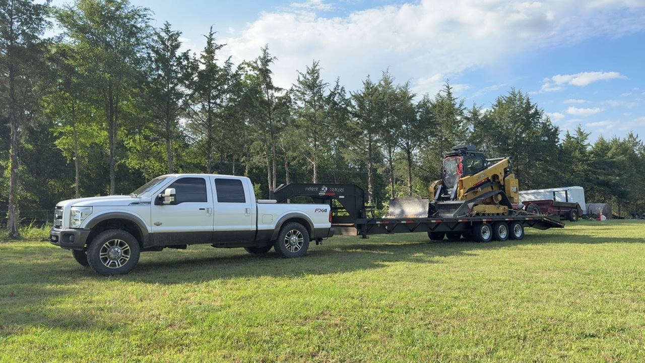 Ford King Ranch truck hauling a CAT skid steer on a gooseneck trailer